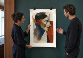 An artist and collector evaluating a large textured fine art paper print against a deep teal gallery wall.