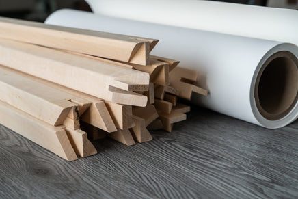 photo of a pile of wooden stretcher bar and a roll of canvas.