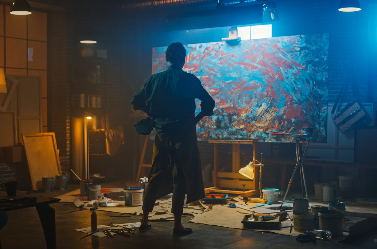 Artist examining an original painting in a studio