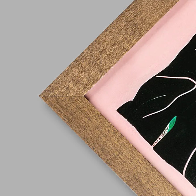 Close-up of a walnut-stain framed print corner with pink artwork