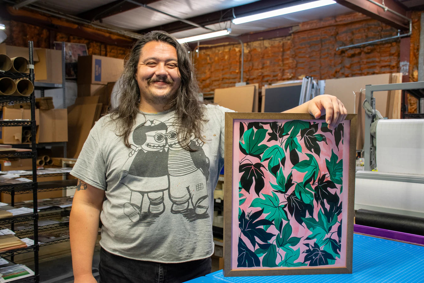 Poppy holding a walnut-stain framed print in the Stackhouse production studio